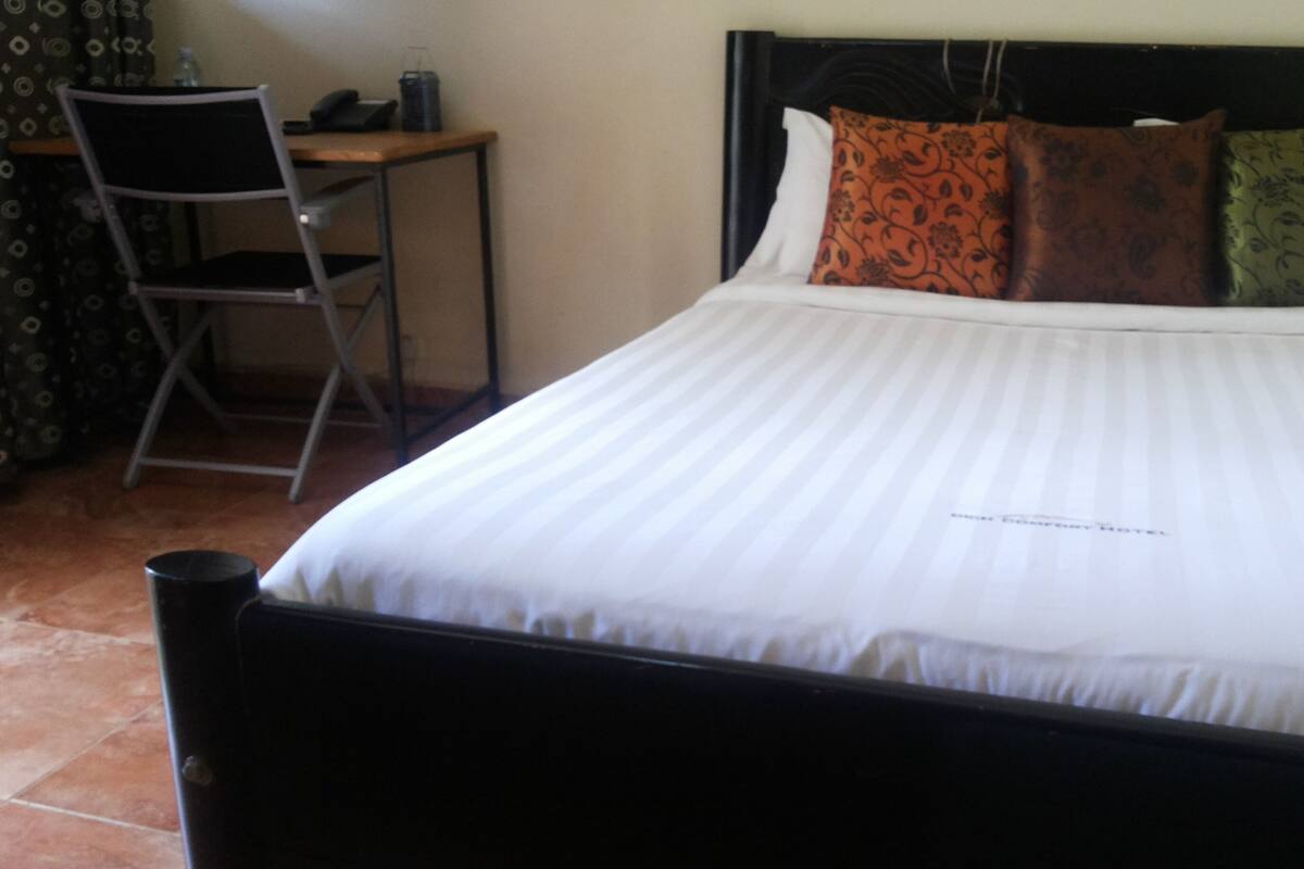 A hotel room with a bed, a desk, and a chair.