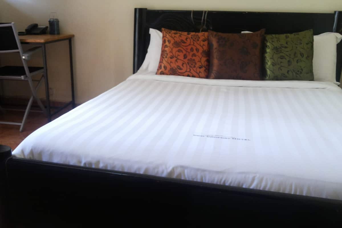 A bed with a headboard, pillows, a bedside table, and a chair.