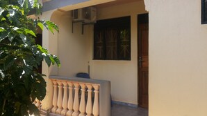 Um edifício com varanda, janela protegida por grades de metal e unidade de ar condicionado na parede.