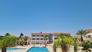 A hotel with a swimming pool, palm trees, and a clear blue sky. - Narcissos 'Nissi Beach' Apartment C3 (Ayia Napa)
