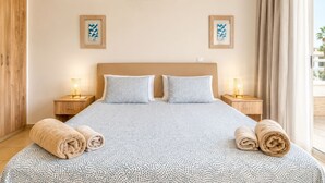 A hotel room with a bed, two nightstands, two framed pictures, and two rolled towels. - Narcissos 'Nissi Beach' Apartment C3 (Ayia Napa)