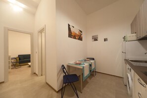 A compact living space with a dining area, a washing machine, and a small kitchen. - La Cattedrale dai Tetti (Trani)