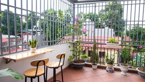 En balkon med plantekasser, to træstole og et lille bord.