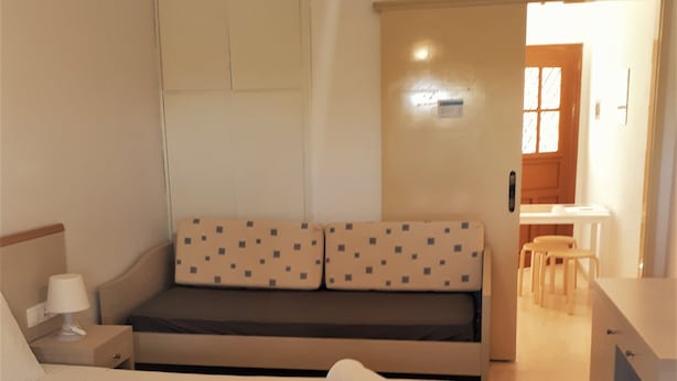Ein Hotelzimmer mit Bett, Schreibtisch, Stuhl, Sofa und einer Pendelleuchte.