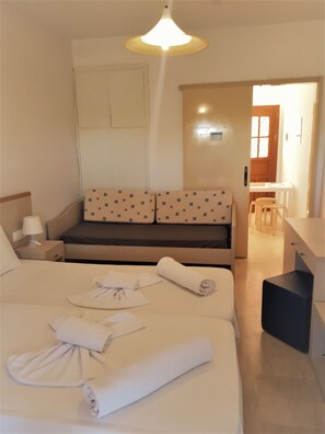 A hotel room with a bed, a desk, a chair, a sofa, and a hanging light fixture. - Sophie Studios (Corfu)