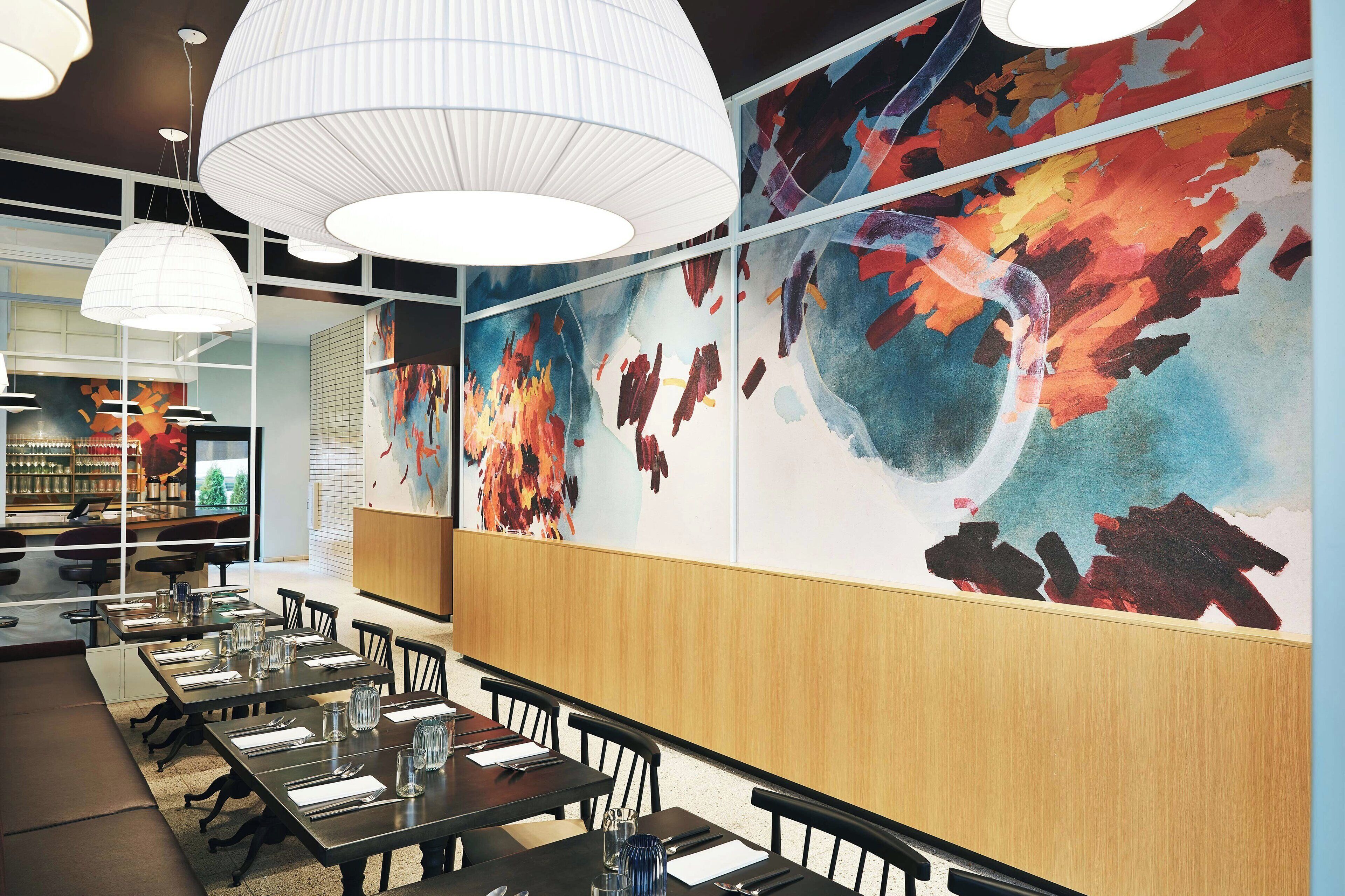 A restaurant interior with high tables, chairs, and modern pendant lighting.