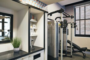 A gym with a wall-mounted exercise machine, a bench, and a potted plant on a counter.
