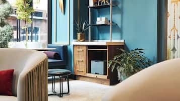 Una sala de estar moderna con una pared azul de acento, un escritorio de madera con cajones, una impresora negra y una planta en maceta.