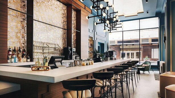 A modern bar area with a long counter, bar stools, and a patterned wall. - Kinley Cincinnati Downtown, a Tribute Portfolio Hotel (Cincinnati)