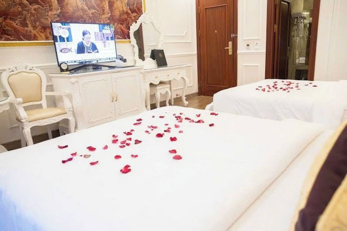 A hotel room with two beds, a desk with a laptop, and a mirror.