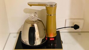 A coffee maker with a digital display on a black and gold base.