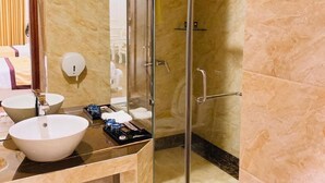 A modern bathroom with a glass-enclosed shower, a large sink, and a toilet.