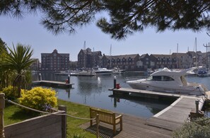 Moored yachts and boats line the marina, surrounded by historic buildings and lush greenery.