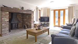 Una sala de estar con chimenea de ladrillo, televisor, sofá y una mesa de centro.