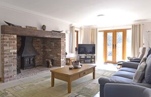Cozy living room with a traditional fireplace, comfortable sofa, and flat-screen TV.