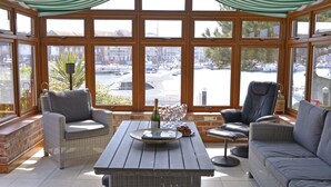 Un solárium con muebles de mimbre, una mesa de madera y vistas a un puerto deportivo.