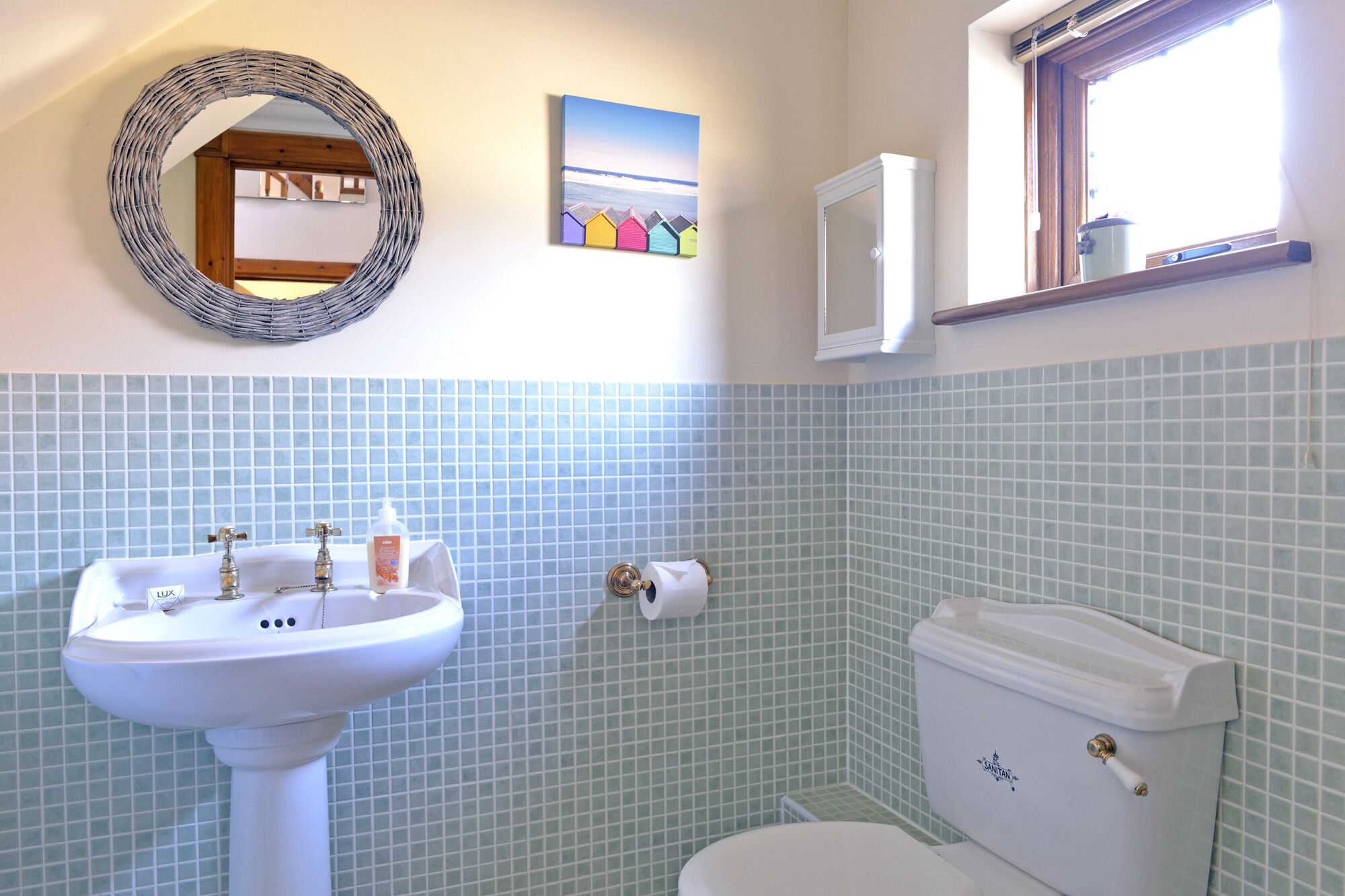 A bathroom with a white sink, a toilet, and a mirror on the wall.
