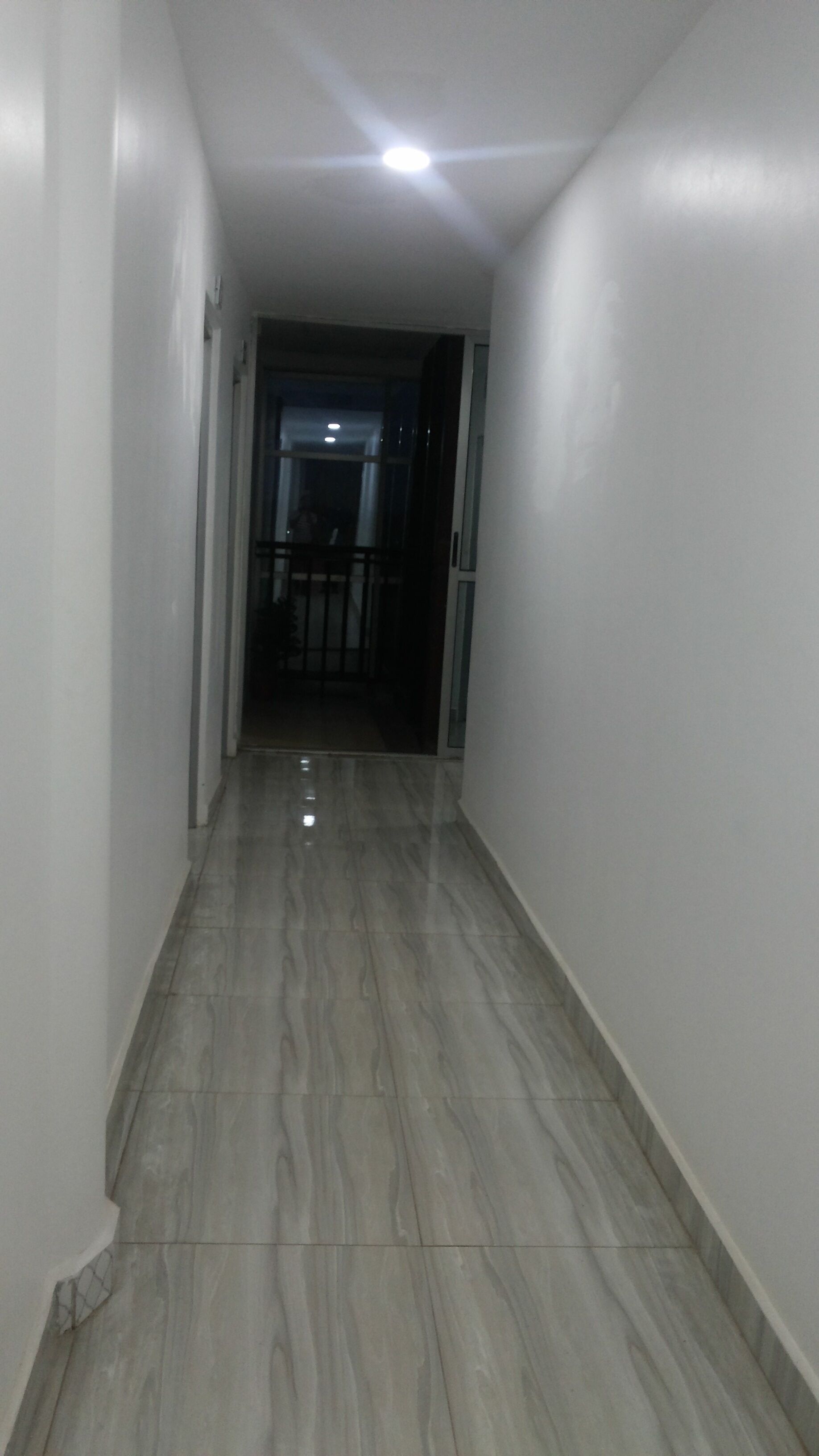A corridor with a marble floor and white walls.