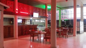 Un restaurant doté d’un bar, de tables et de chaises en bois, et d’un sol carrelé.