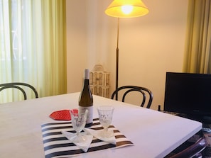 A dining table with a bottle of wine, two glasses, and a red coaster.