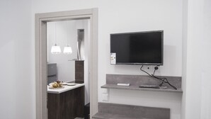 A modern bathroom with a vanity, a mirror, a television mounted above the counter, and a towel rack. - InCity La Central 203, Deluxe Flat (Thessaloniki)