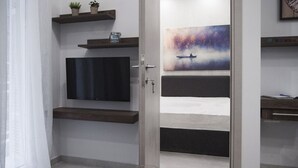 A modern bedroom with a bed, a TV, and a painting of a boat on water. - InCity La Central 203, Deluxe Flat (Thessaloniki)