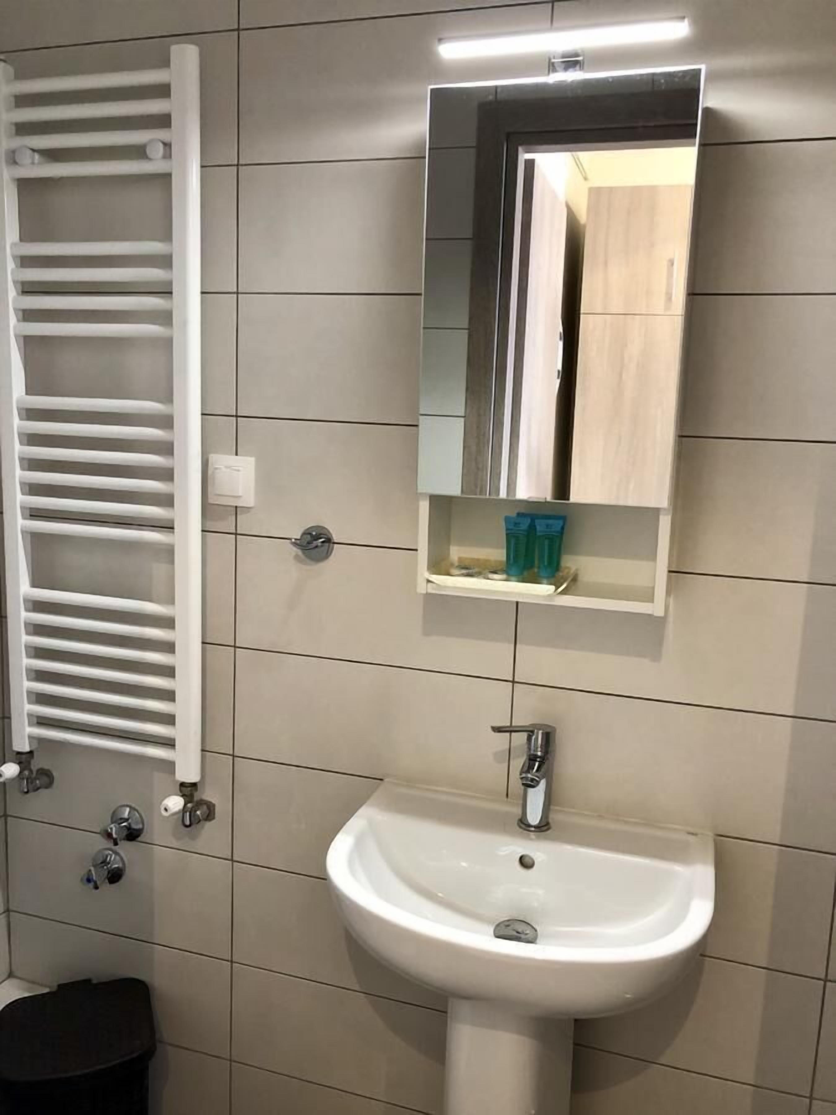 Een badkamer met een witte wastafel, een spiegel en een handdoekhouder.