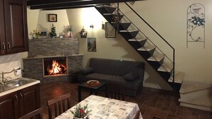 Una sala de estar acogedora con chimenea, un sofá, una mesita de centro y una escalera.