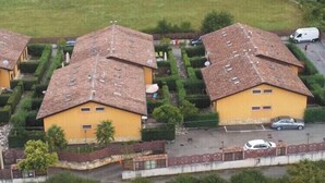 Zona residencial con dos casas amarillas, cada una con tejado de baldosas y un pequeño jardín.