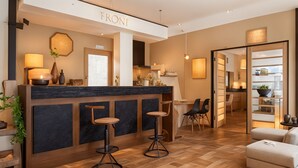 En moderne hotellobby med reception, siddeområde og udsigt til køkkenet.