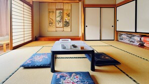 Et traditionelt japansk rum med tatamigulv, et lavt bord med en telefon og en shoji-skærm med kunstværk.