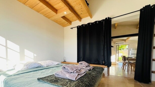 Een slaapkamer met twee bedden, een houten plafond en uitzicht.
