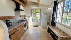 Een keuken met houten kastjes, een gasfornuis, een magnetron en een koelkast.
