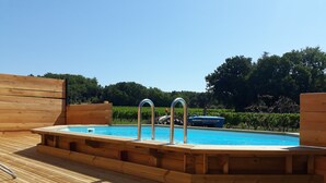 Een houten terras met een rechthoekig whirlpool en een zwembad.