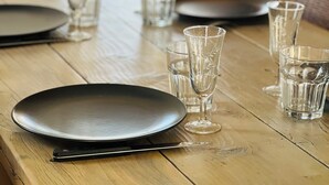 Een houten eettafel met borden, glazen en bestek.
