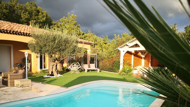 A swimming pool surrounded by a well-maintained lawn, a pergola, and a small garden area with a tree and outdoor furniture. - House in the heart of green Provence and 35 minutes from the beaches (Gareoult)
