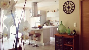 A modern kitchen with white cabinets, a central island, and a dining area with a table and chairs. - House in the heart of green Provence and 35 minutes from the beaches (Gareoult)