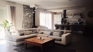 A modern living room with a sectional sofa, a coffee table, and a kitchen in the background. - House in the heart of green Provence and 35 minutes from the beaches (Gareoult)
