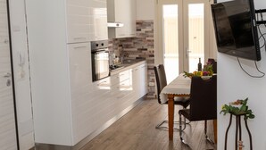 A modern kitchen with white cabinets, a built-in oven, and a tiled backsplash. - Sicily Bedda vacation home, apartment in the city center and a stone's throw from the sea! (Pozzallo)
