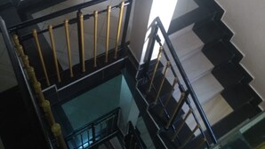 A multi-level interior with a central staircase, black and white tiled floors, and a glass railing.