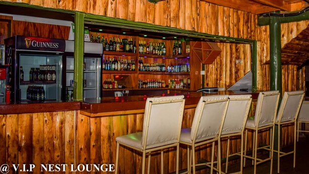 A bar area with a wooden interior, a Guinness refrigerator, and multiple liquor bottles.