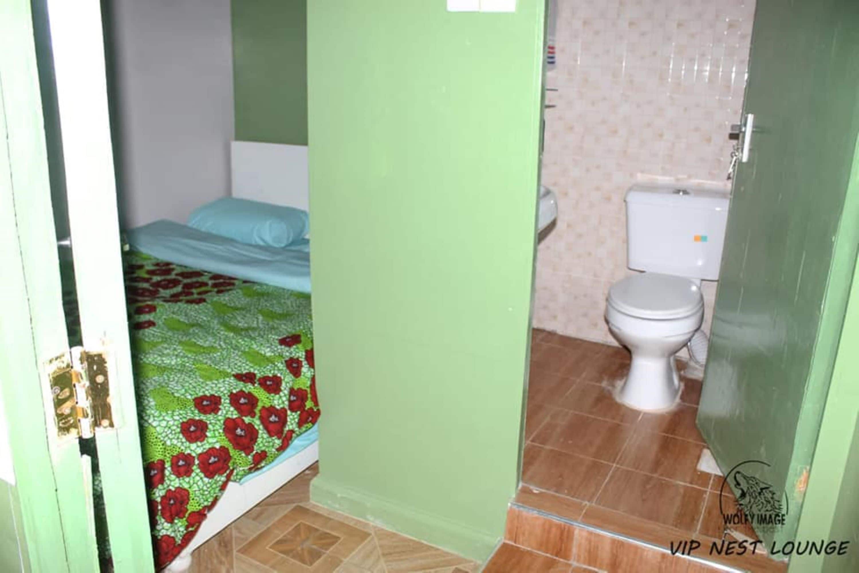 Une petite pièce étroite, avec un lit et des toilettes.