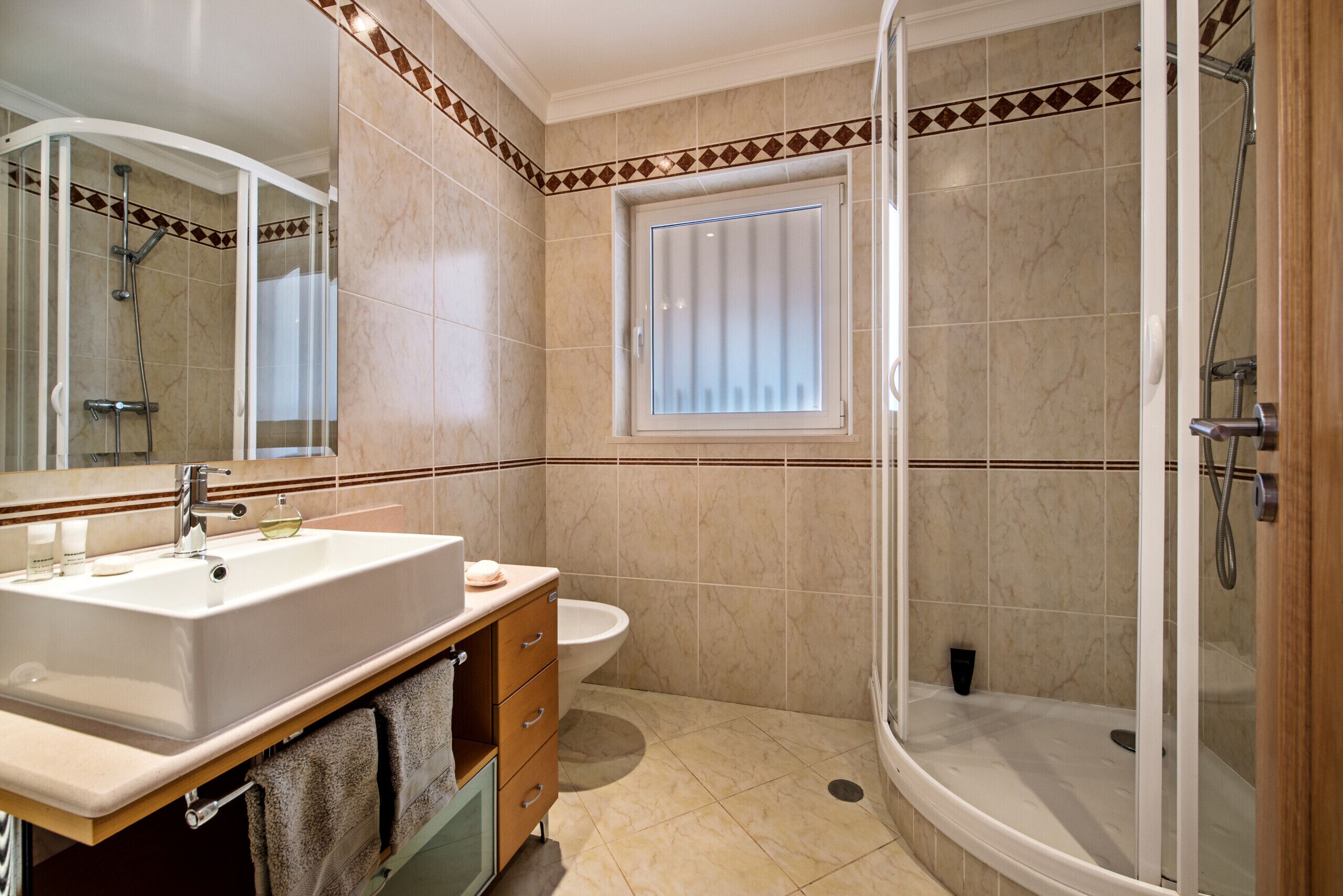 A bathroom with a sink, mirror, vanity, toilet, and a glass-enclosed shower.