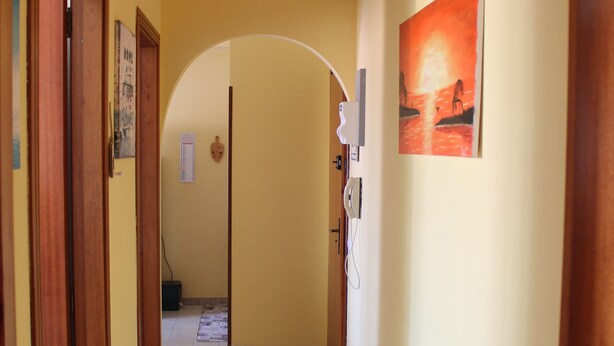 Een gang met houten deuren, een betegelde vloer en een schilderij aan de muur.
