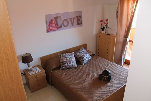A bedroom with a bed, a nightstand, a dresser, and a wall decoration.