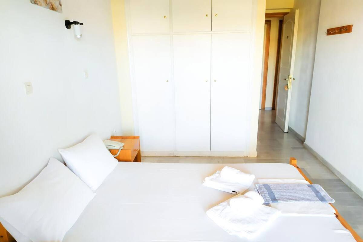 Une chambre à coucher avec un lit, deux oreillers, une table de chevet, une armoire et une porte de salle de bain.