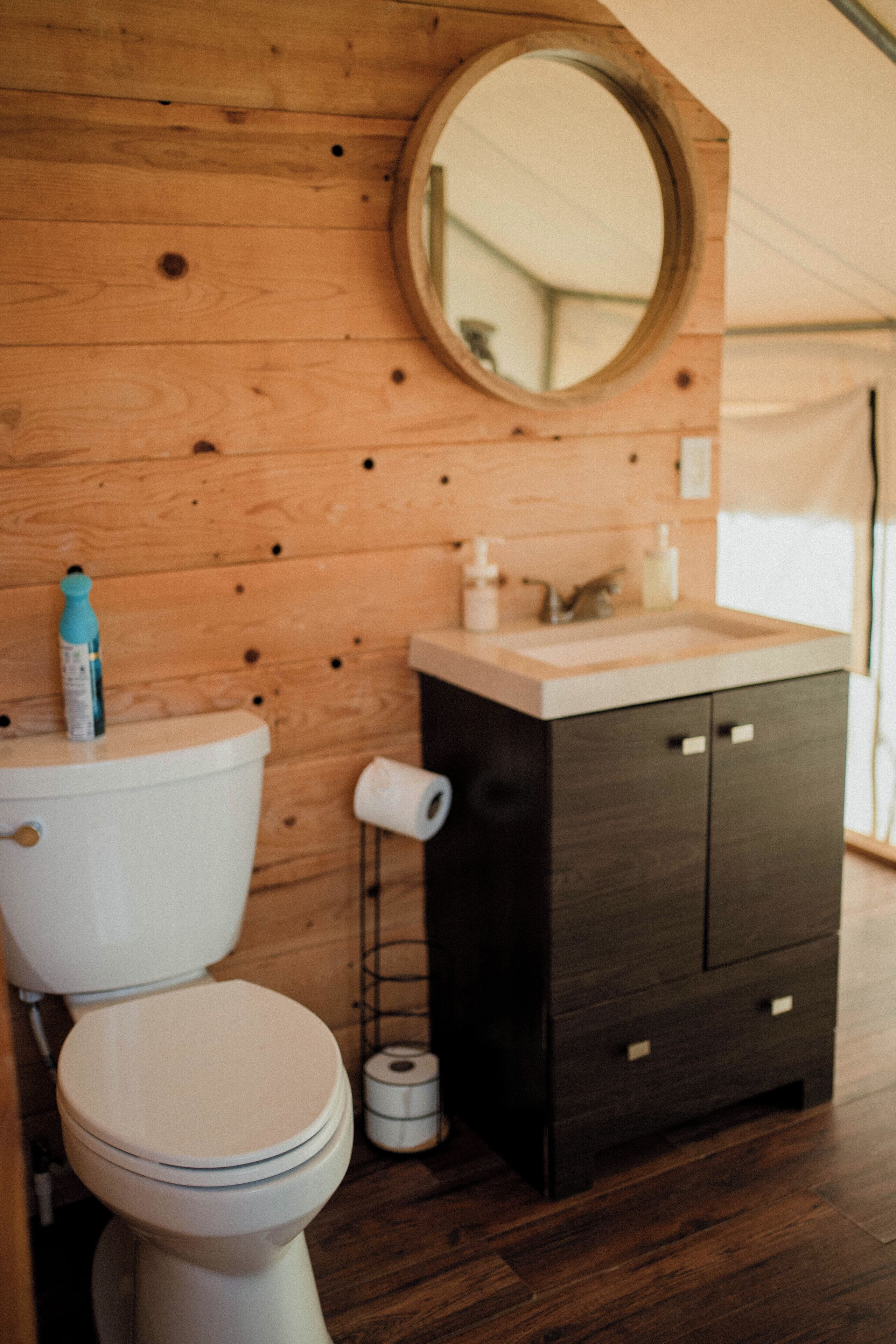 A wooden bathroom with a toilet, a sink, and a mirror.