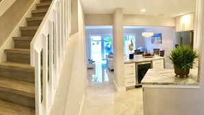 A modern kitchen with a built-in dishwasher, a dining area with a table and chairs, and a staircase leading to another level.