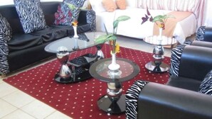 Ein Wohnzimmer mit einem roten Teppich mit Muster, schwarzen und weißen Sofas mit Muster und einem Glastisch mit Blumenvase.