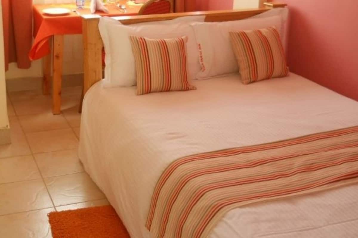 Quarto com cama, mesa de madeira e uma cadeira.